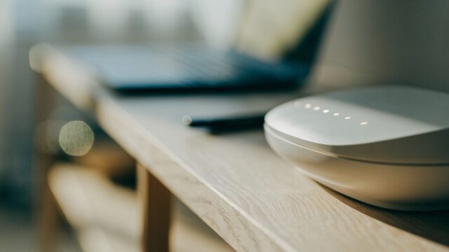 A home wifi router with softly glowing indicator lights on a shelf