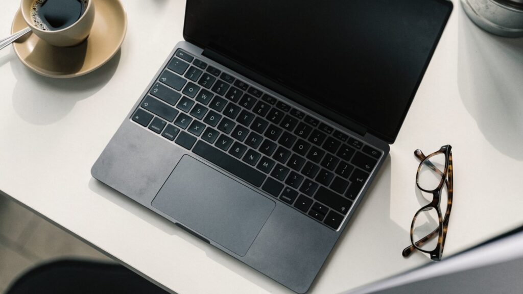 A person seen from behind using a graphite black laptop on a sofa