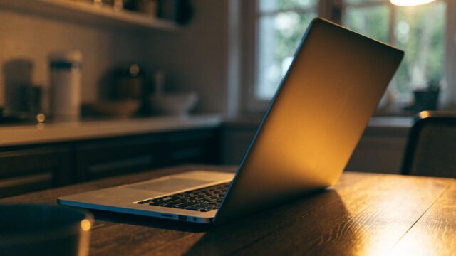 A half-closed silver laptop on a kitchen table