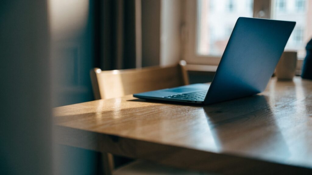 A half-closed dark blue laptop on a wooden desk