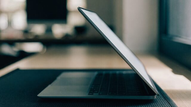 A half-closed matte grey laptop on a dark desk mat