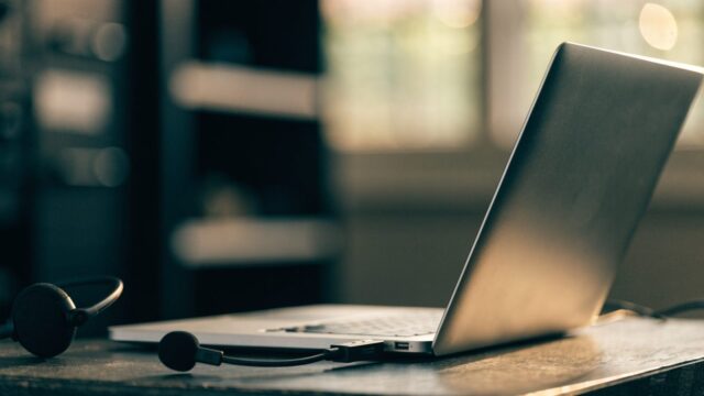 A USB headset with microphone plugged into a silver laptop on a workbench