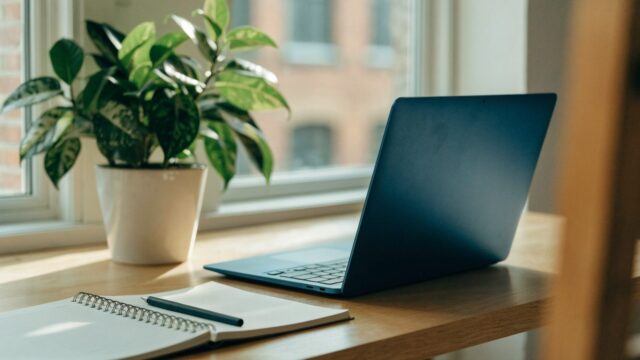 A tidy home office desk with a dark blue laptop