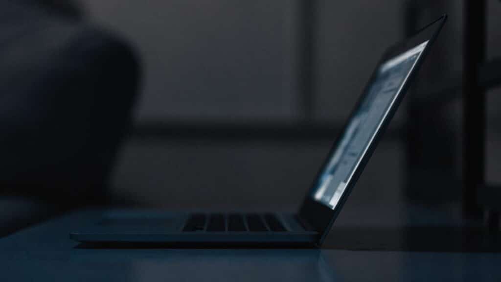 A dark blue laptop in a dark room