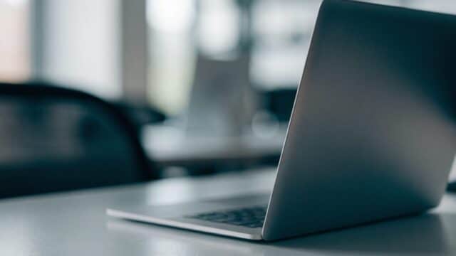A silver laptop on an office desk with a completely dark blank screen