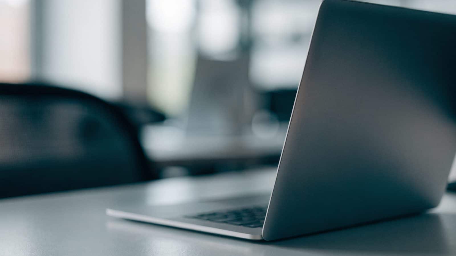 A silver laptop on an office desk with a completely dark blank screen