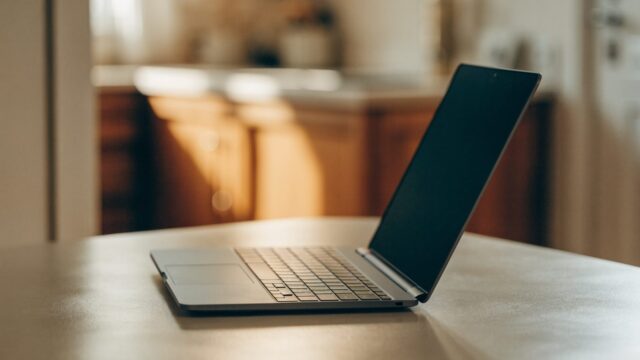 A matte grey laptop on a kitchen table with a completely dark blank screen