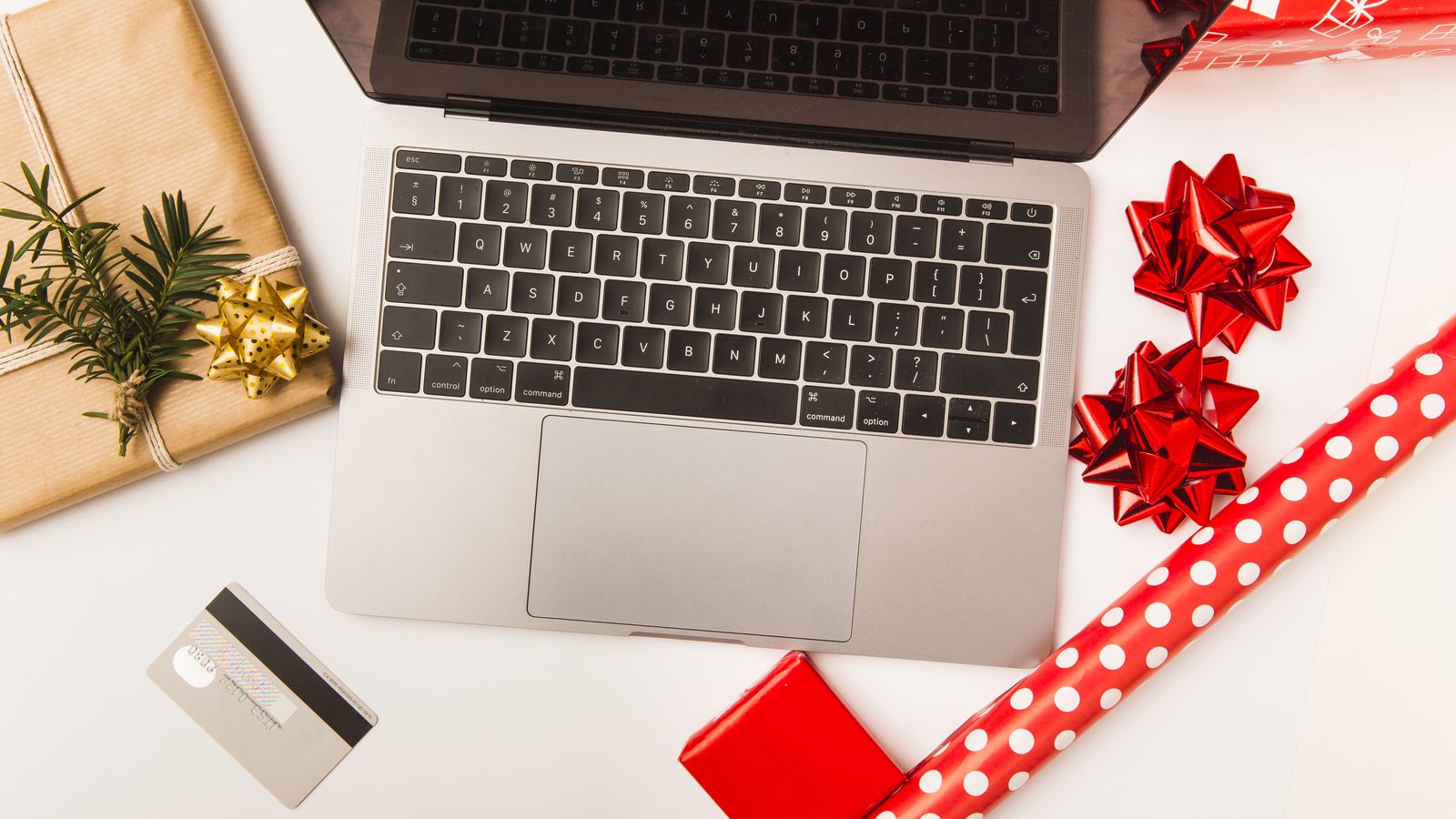 Laptop and credit card with Christmas wrapped gift on table