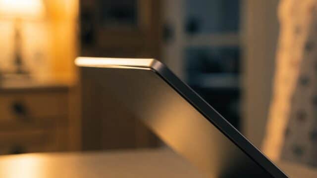 Close-up of the hinge and screen edge of a graphite black laptop on a kitchen table