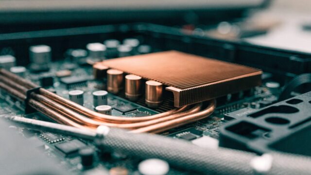 Close-up of a laptop motherboard with copper heat pipes during a repair