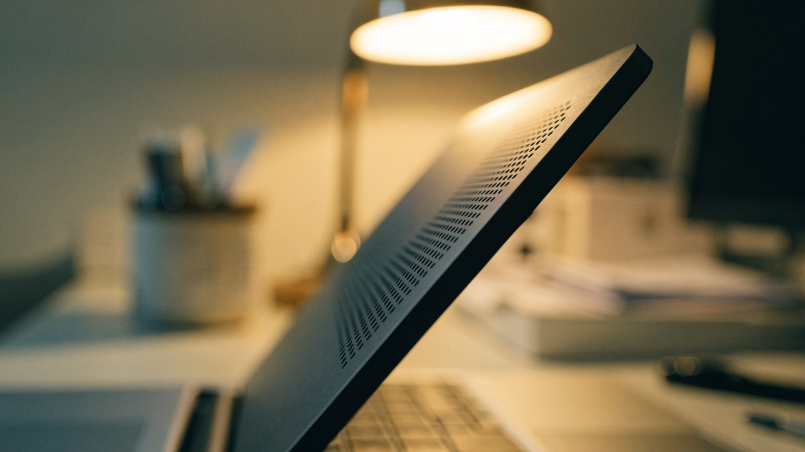 Close-up of the speaker grille edge of a graphite black laptop on an office desk
