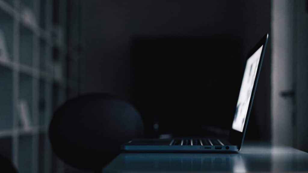 A dark blue laptop in a dark room