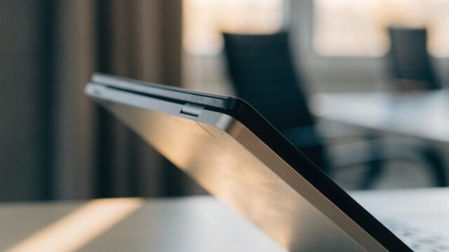 Close-up of the hinge and screen edge of a silver laptop on an office desk