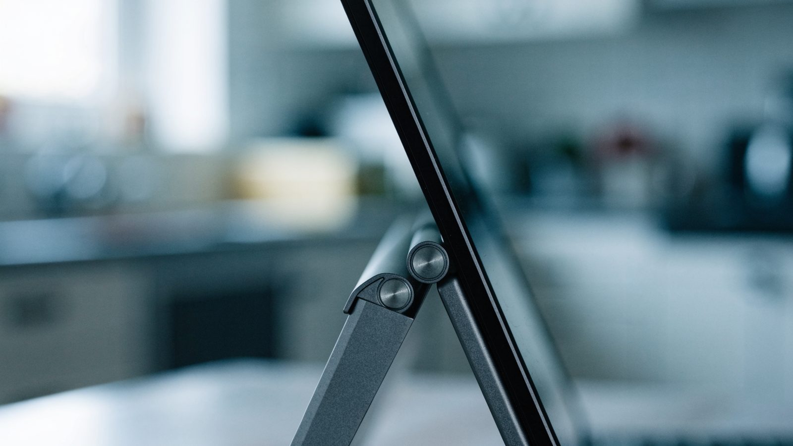 Close-up of the hinge and screen edge of a graphite black laptop on a kitchen table