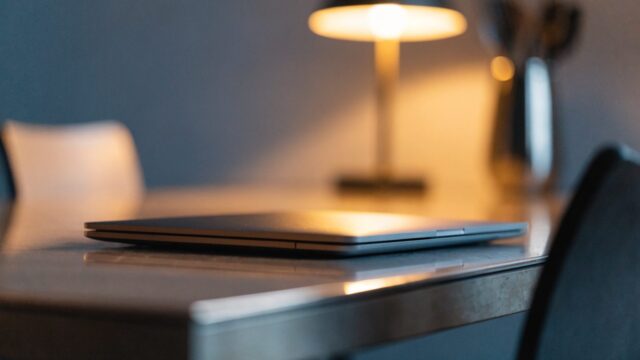 A sleek modern matte grey laptop centered on a kitchen table against a clean soft gradient background