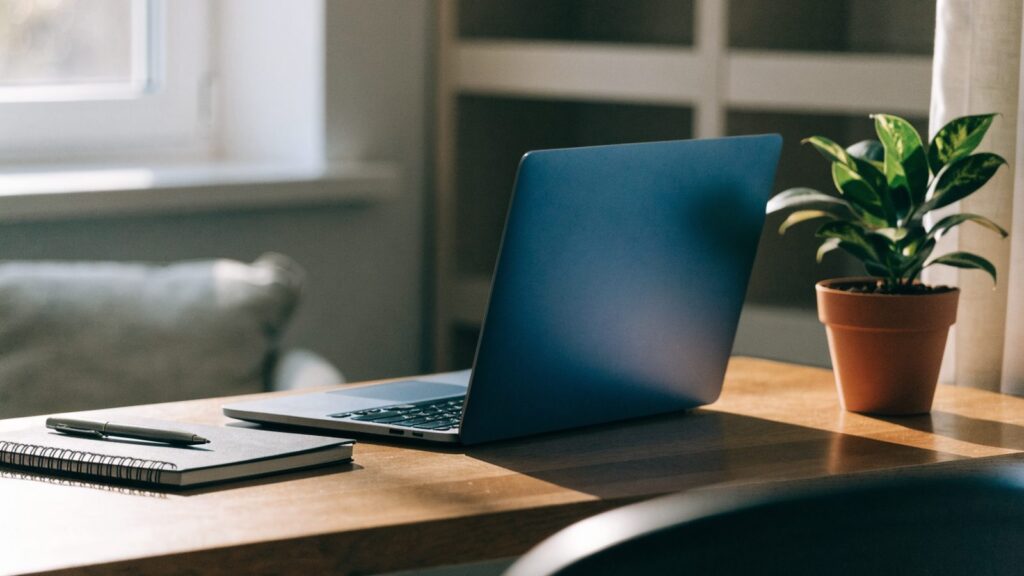 A tidy home office desk with a dark blue laptop