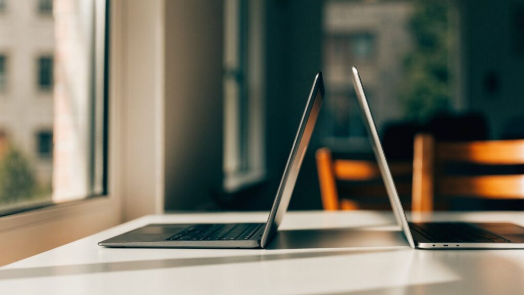 Two laptops side by side on a white desk as if being compared