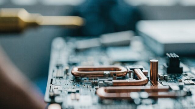 Close-up of a laptop motherboard with copper heat pipes during a repair