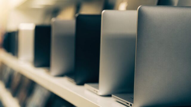 A row of new laptops on display on a store shelf