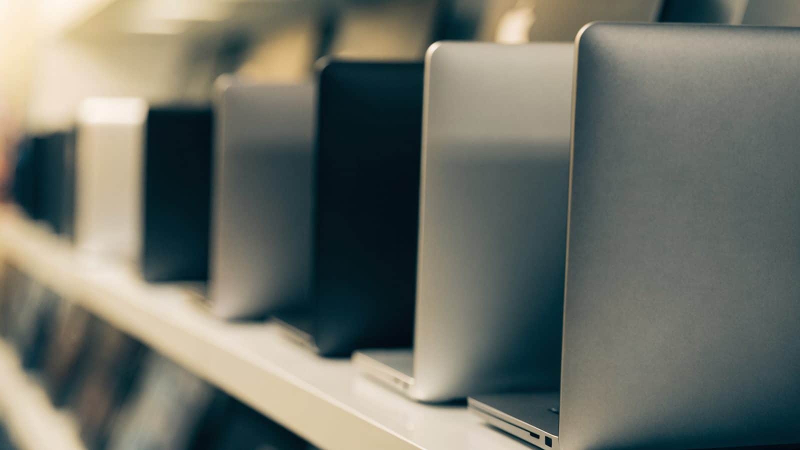 A row of new laptops on display on a store shelf