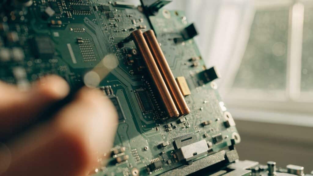 Close-up of a laptop motherboard with copper heat pipes during a repair