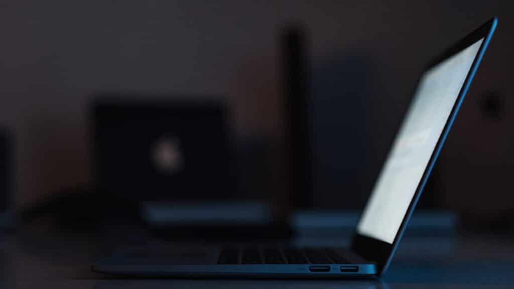A dark blue laptop in a dark room