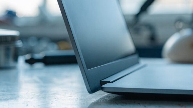 Close-up of the hinge and screen edge of a matte grey laptop on a workbench