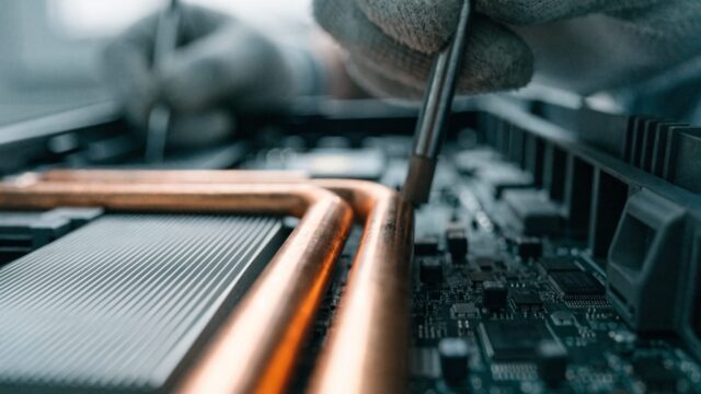 Close-up of a laptop motherboard with copper heat pipes during a repair