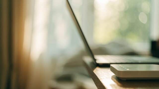 A home wifi router with softly glowing indicator lights on a shelf